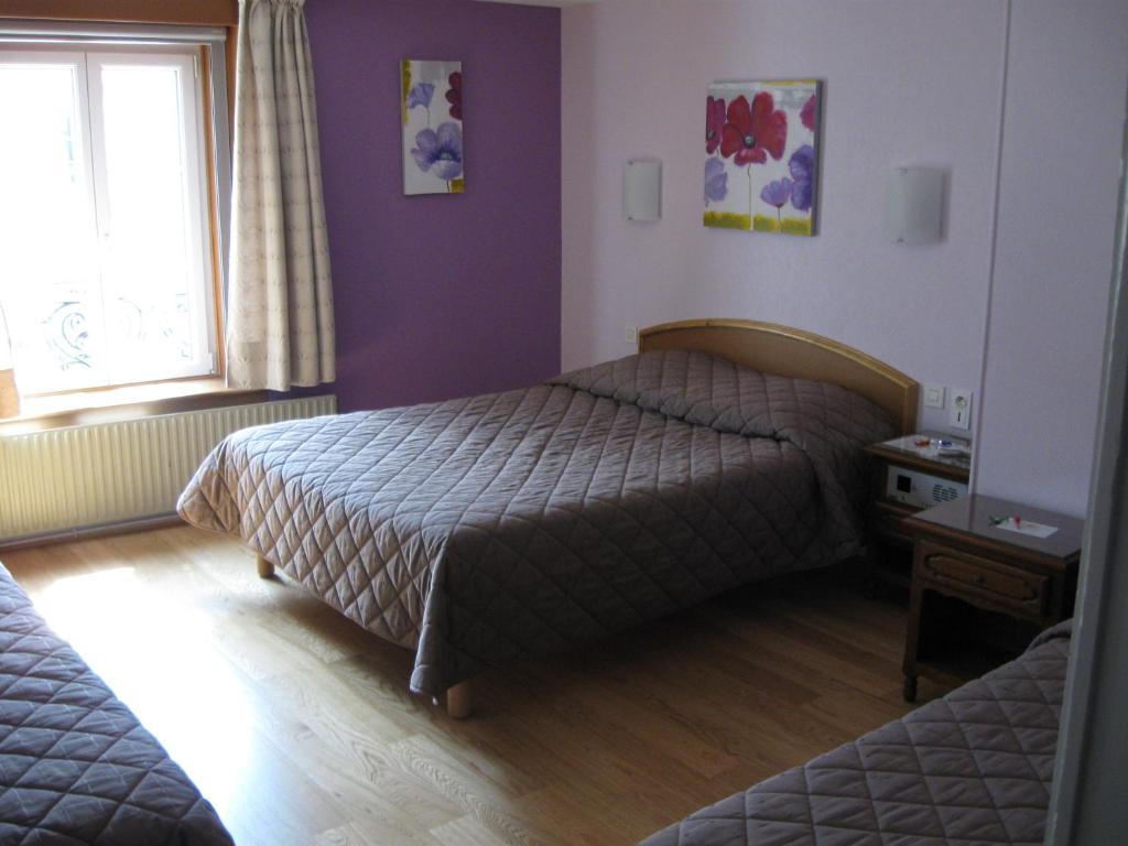 a bedroom with two beds and a window at Hotel Cheval De Bronze in Remiremont