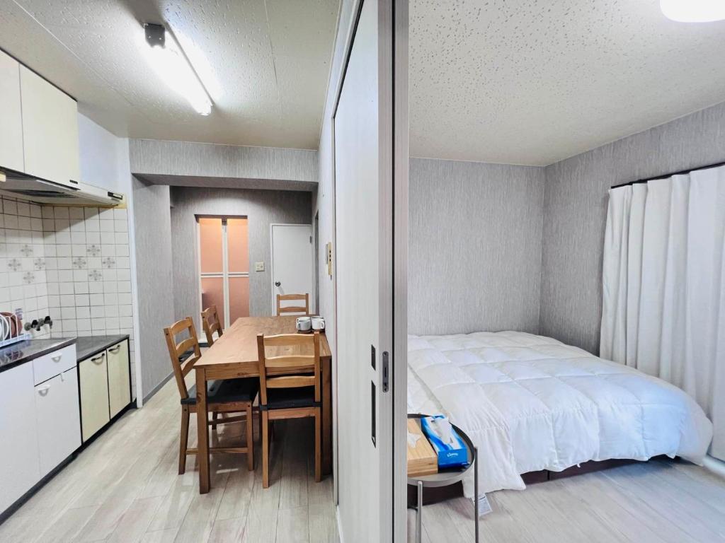 a bedroom with a bed and a table and a kitchen at The Kojima in Tokyo