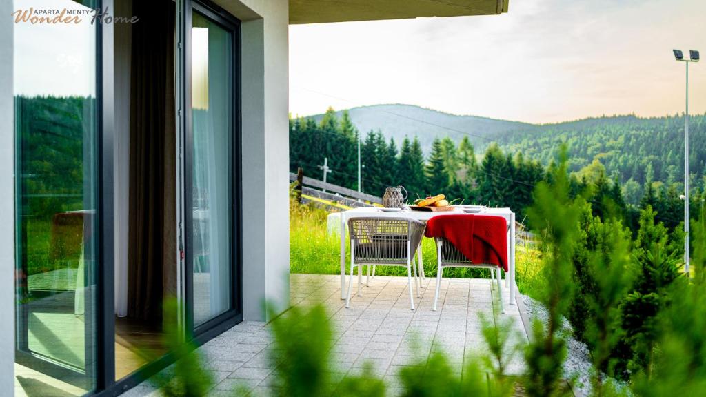 a table and chairs on a balcony with a view at Wonder Home - Domki Hillside tuż przy stoku narciarskim - na terenie kompleksu plac zabaw i zewnętrzna siłownia in Karpacz