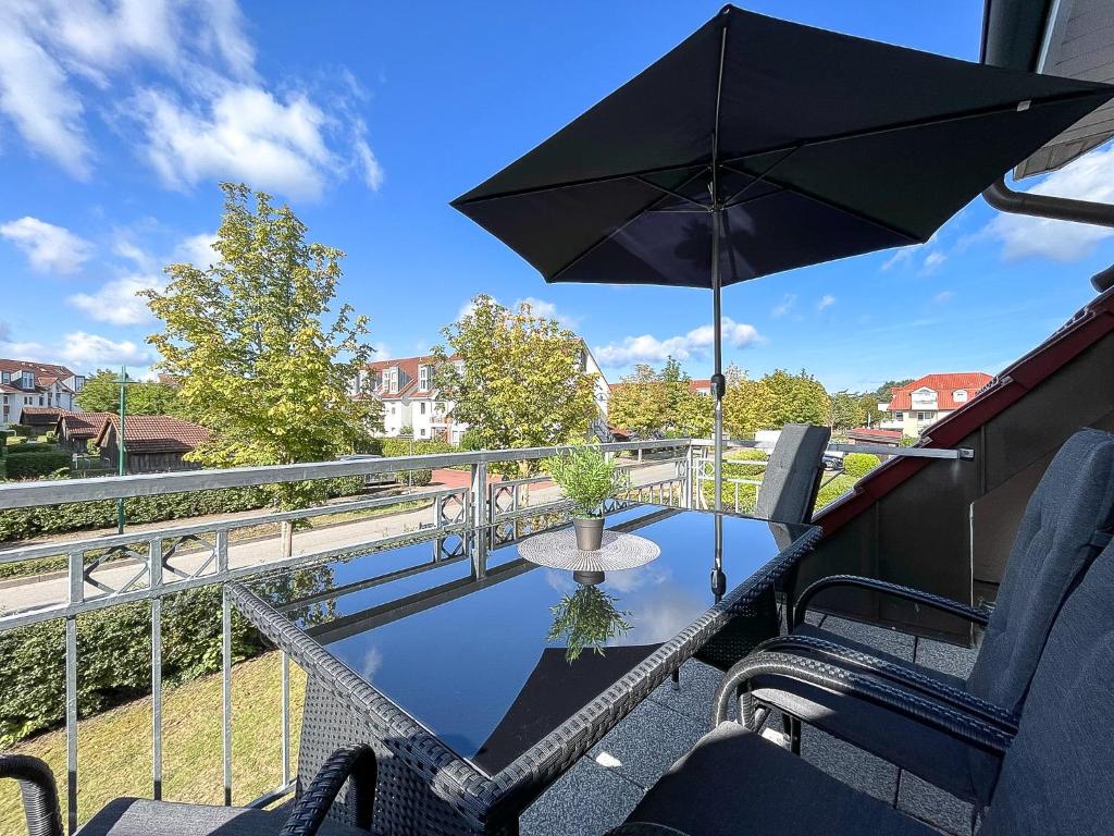 a table with an umbrella and chairs on a balcony at Luisa Wohnung 3 in Boltenhagen