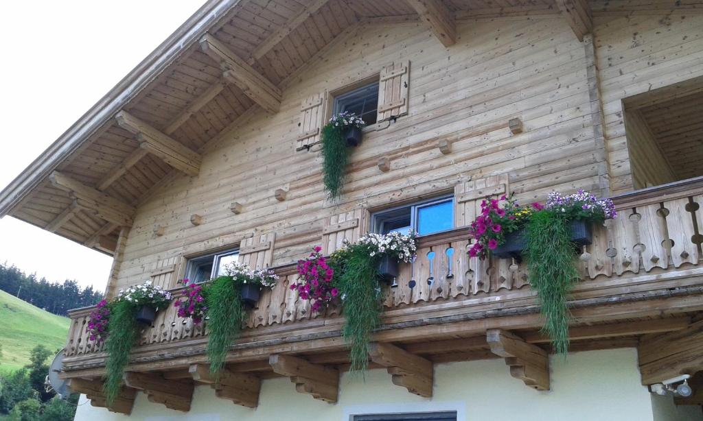 ein Holzhaus mit Blumen auf dem Balkon in der Unterkunft Appartement Haus Pichler in Leogang