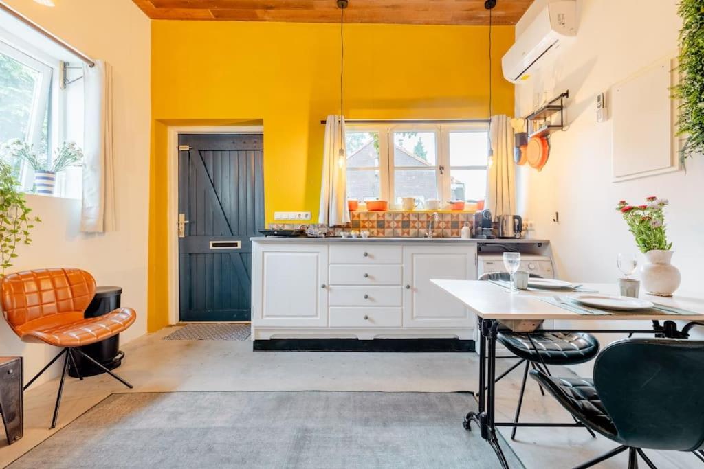 uma cozinha com paredes amarelas e uma mesa e cadeiras em The Corner House em Kampen
