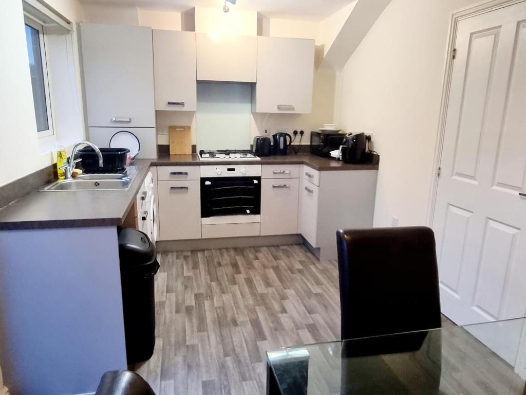 a kitchen with white appliances and a glass table at Stunning 3 bed home at the heart of Wolverhampton in Wolverhampton