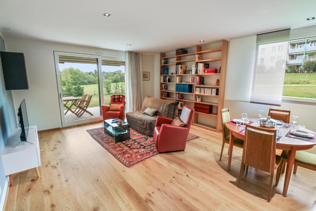 a living room with a table and a dining room at Appartement élégant avec terrasse privée in Villars-sur-Glâne