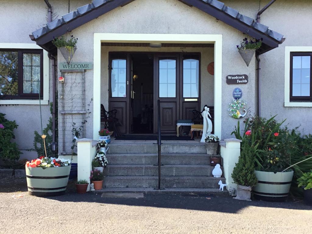 uma porta da frente de uma casa com flores em vasos em Woodcockfaulds House em Stirling