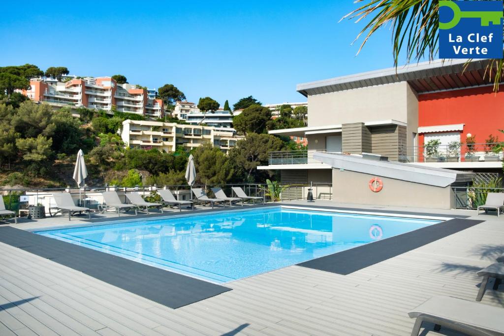 a swimming pool with chairs and a building at Résidence Pierre & Vacances Premium Julia Augusta in Roquebrune-Cap-Martin