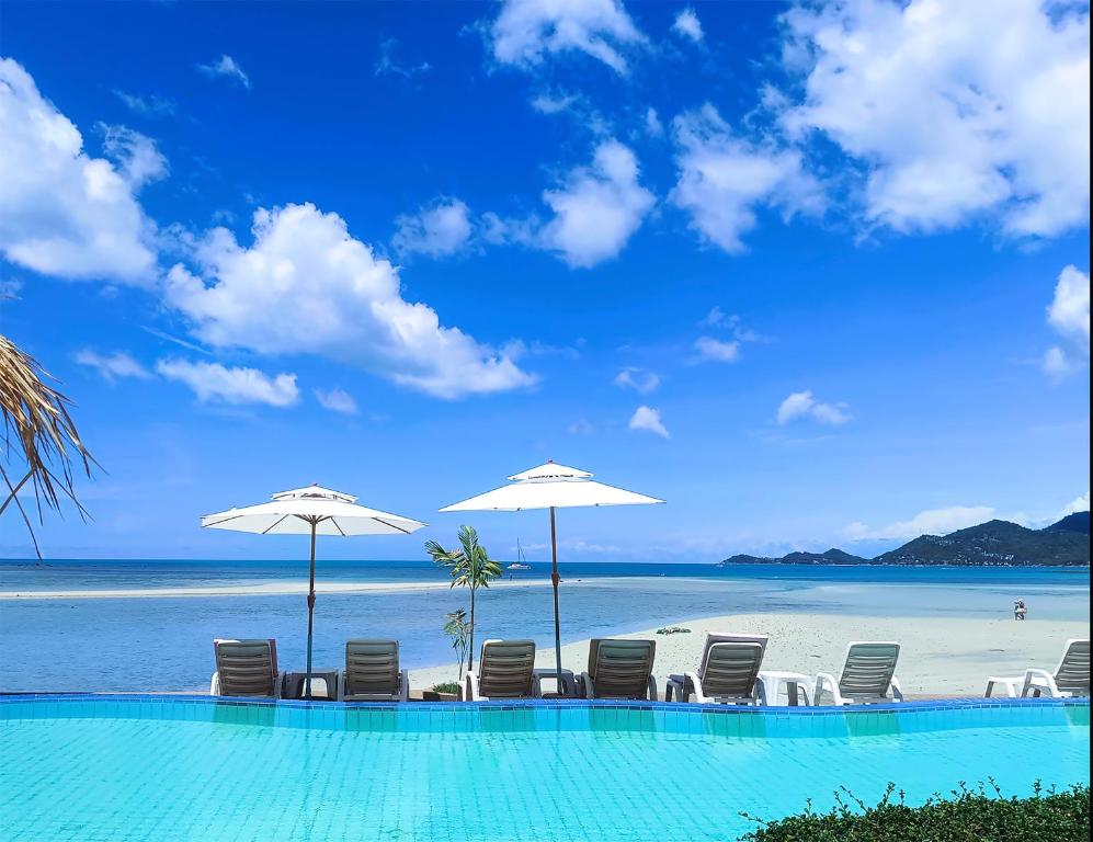 a swimming pool with chairs and umbrellas on a beach at Smile Samui Chaweng Beach Resort in Chaweng