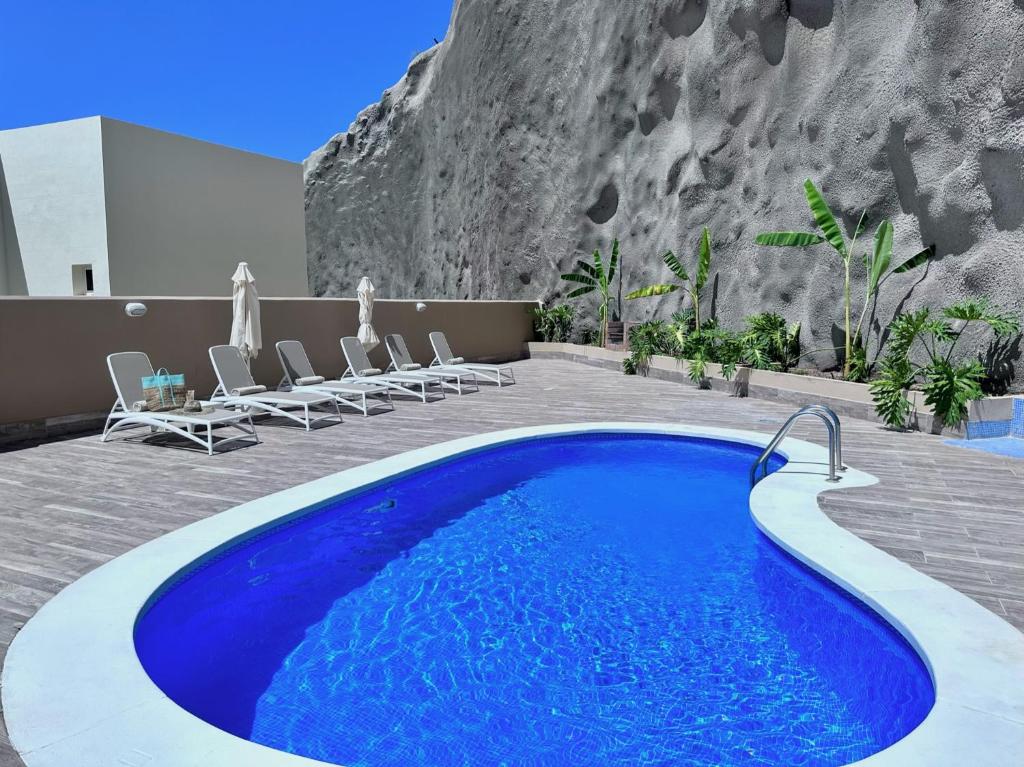 a swimming pool with chairs and a mountain at Luxury Villa Ifara Private Heated Pool in Adeje
