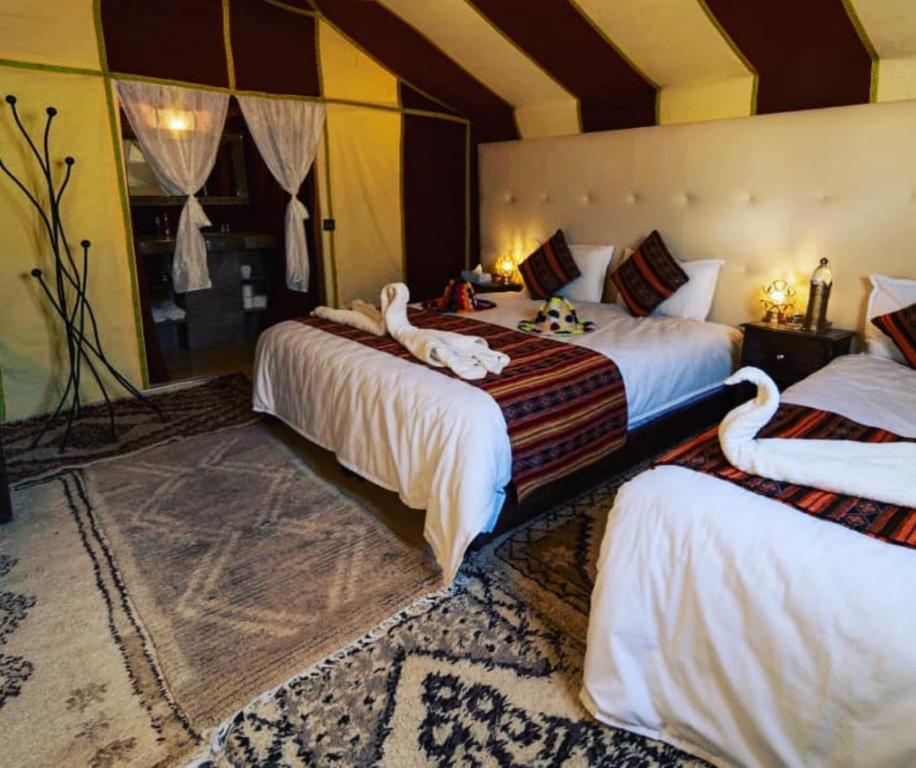 a bedroom with two beds with swans on them at Holiday Desert Camp in Merzouga