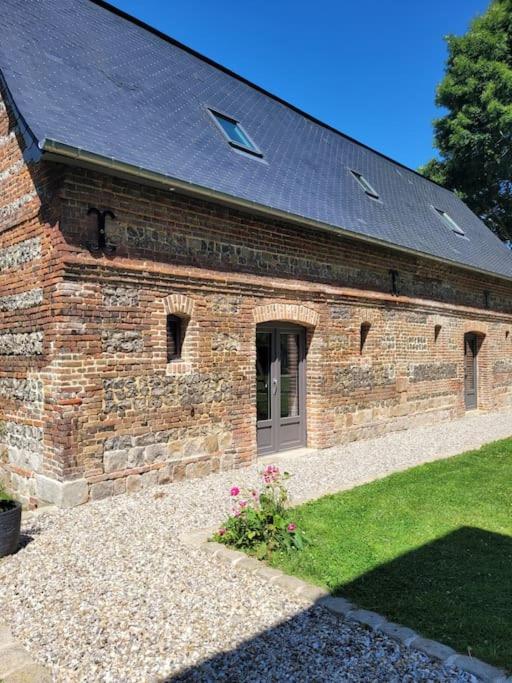 un bâtiment en briques avec une porte dans une cour dans l'établissement Location maison proche mer, à Canville-les-Deux-Églises