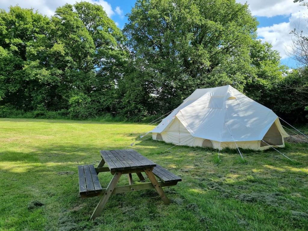 a picnic table and a tent in a field at Glamping in style Emperor tent in Ifield