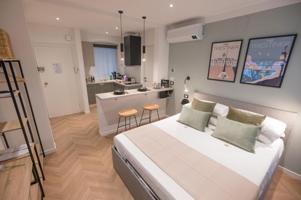 1 Schlafzimmer mit einem großen weißen Bett und einer Küche in der Unterkunft Monte 21 - San Giusto in Triest