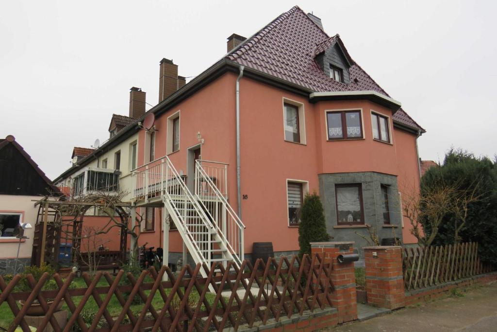 a large orange house with a white staircase on it at Ferienwohnung am Technikmuseum in Dessau
