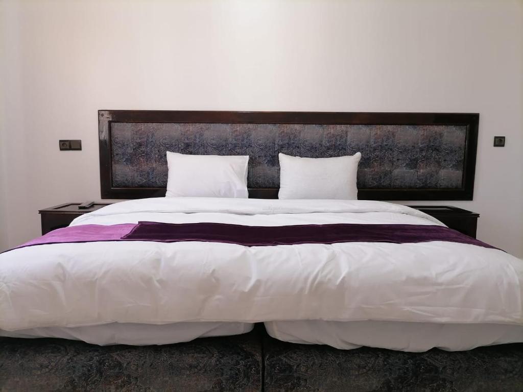 a bedroom with a large white bed with two pillows at HOTEL NASSIM AL-BAHR in Dakhla