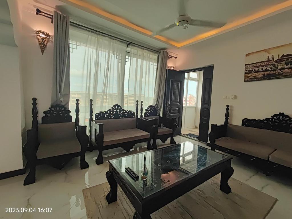 a living room with couches and a glass table at Ayaa Luxury Apartment 4th Floor Zanzibar in Zanzibar City