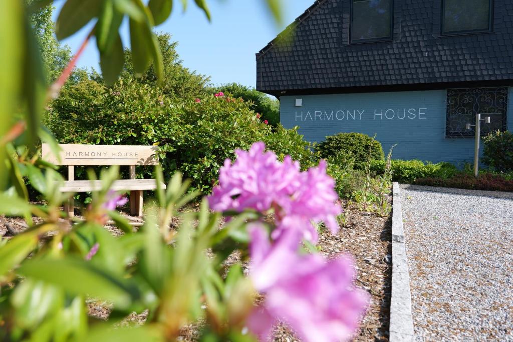 una casa con un banco y flores delante de ella en Harmony House, en Handewitt