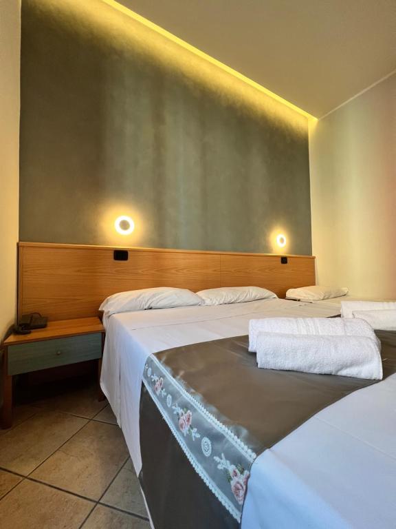 ミラノにあるホテル サラのベッド2台 壁に照明2つが備わる客室です。