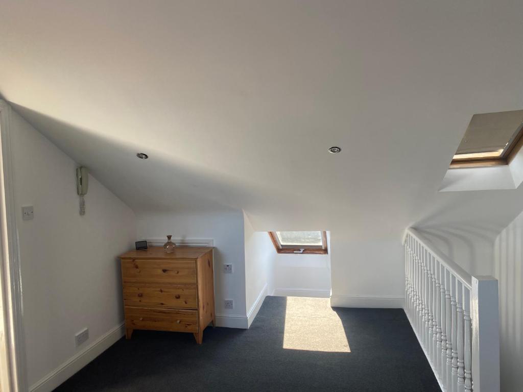um quarto no sótão com uma escada e uma cómoda em madeira em Studio Flat em Hatch End