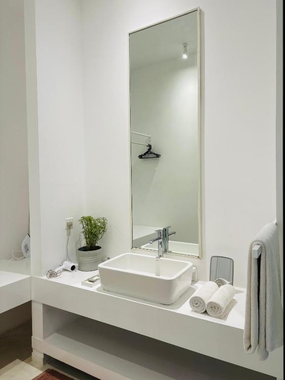 a white bathroom with a sink and a mirror at Saffron Robes Living in Hikkaduwa
