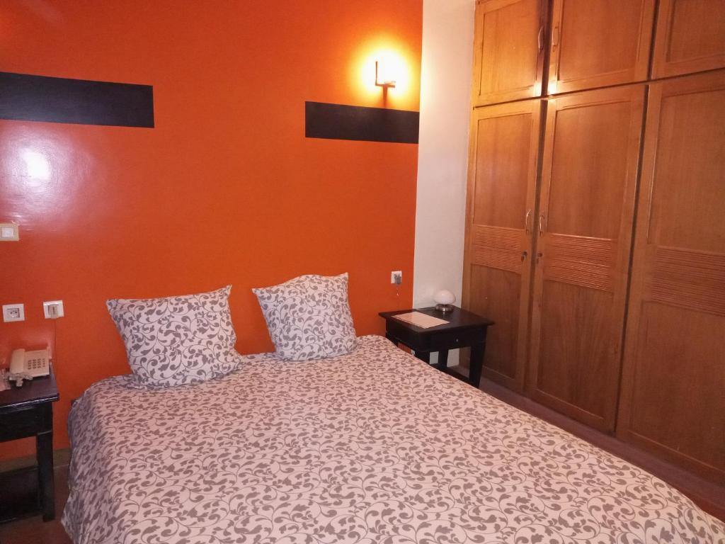 ein Schlafzimmer mit einem Bett mit einer orangefarbenen Wand in der Unterkunft Le ZaNaLi Hotel in Ouagadougou