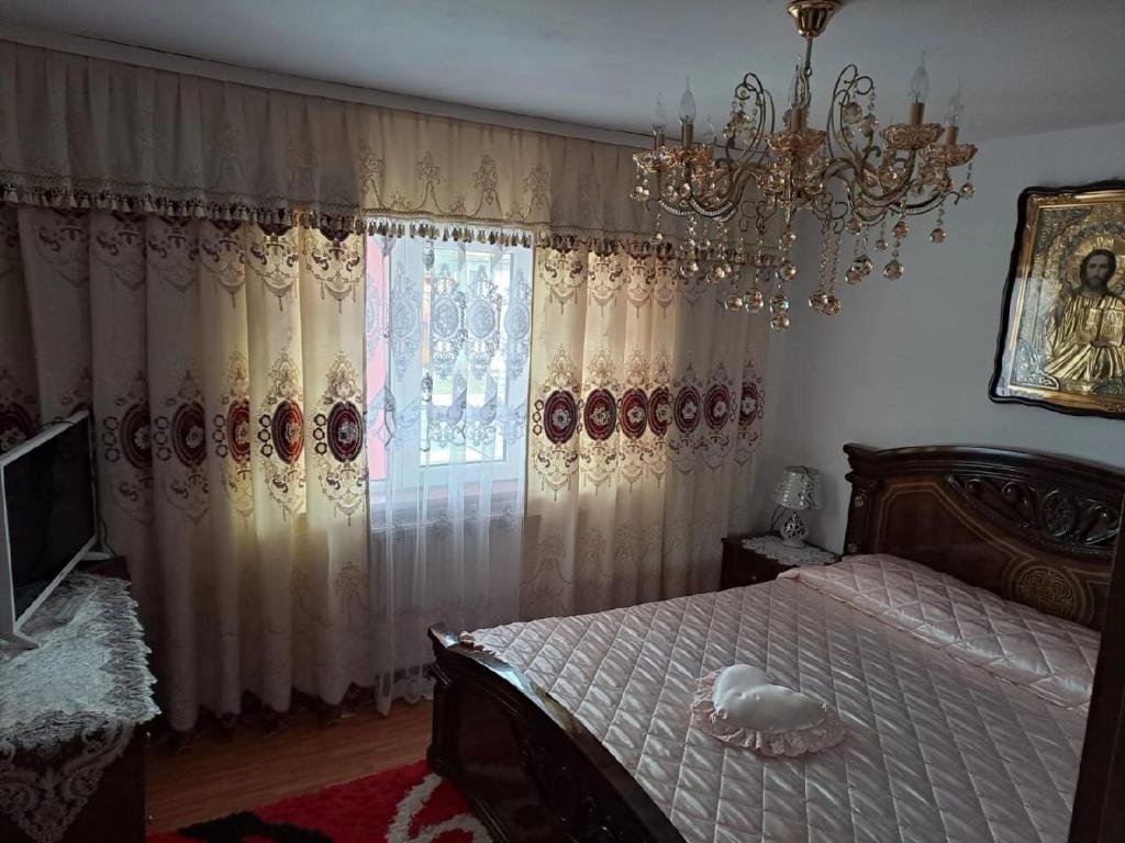 una camera con letto, lampadario a braccio e finestra di Pensiunea Floare de Bucovina a Frasin