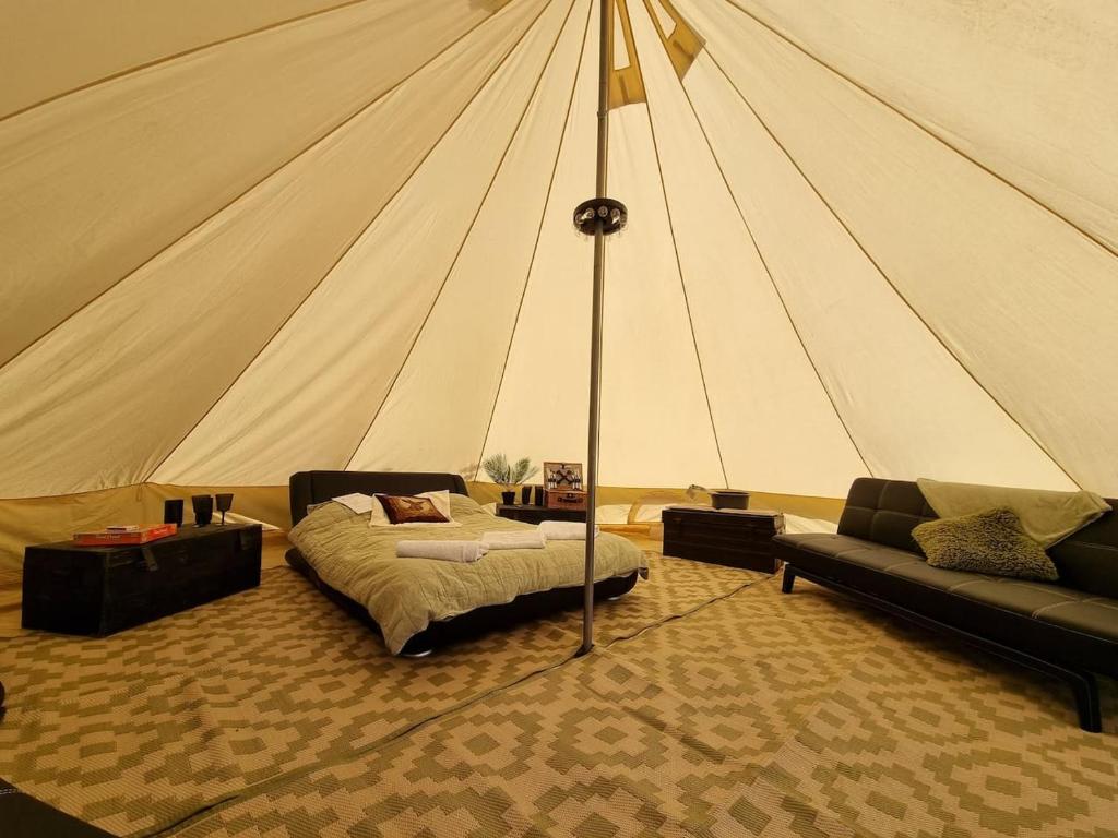 a tent with a bed and a couch in a room at Glamping in style Bell tent in Ifield