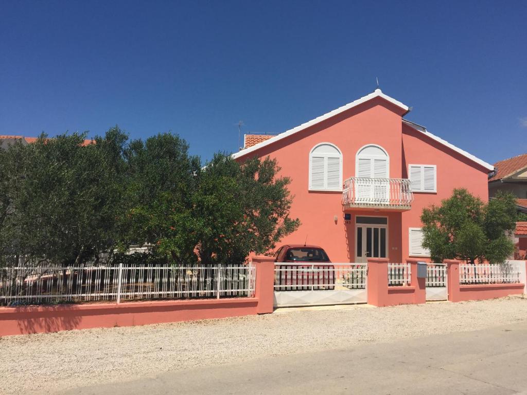 una casa rosa con una recinzione bianca davanti di Apartments Bibic a Vodice