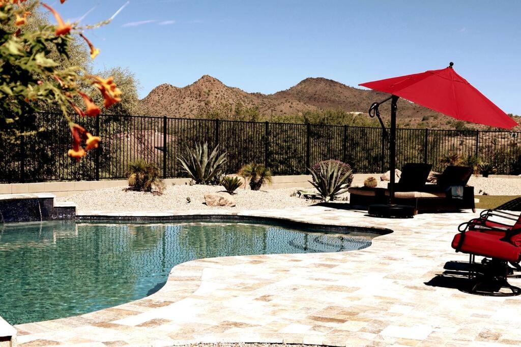 una piscina con una sombrilla roja en un patio en Phoenix Home with heated pool, desert views & hot tub en Anthem