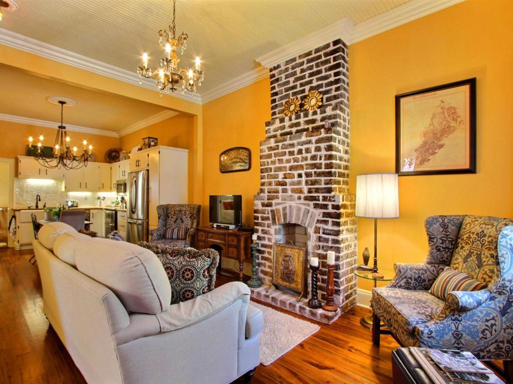 a living room with a brick fireplace and chairs at Coral Cottage in Savannah