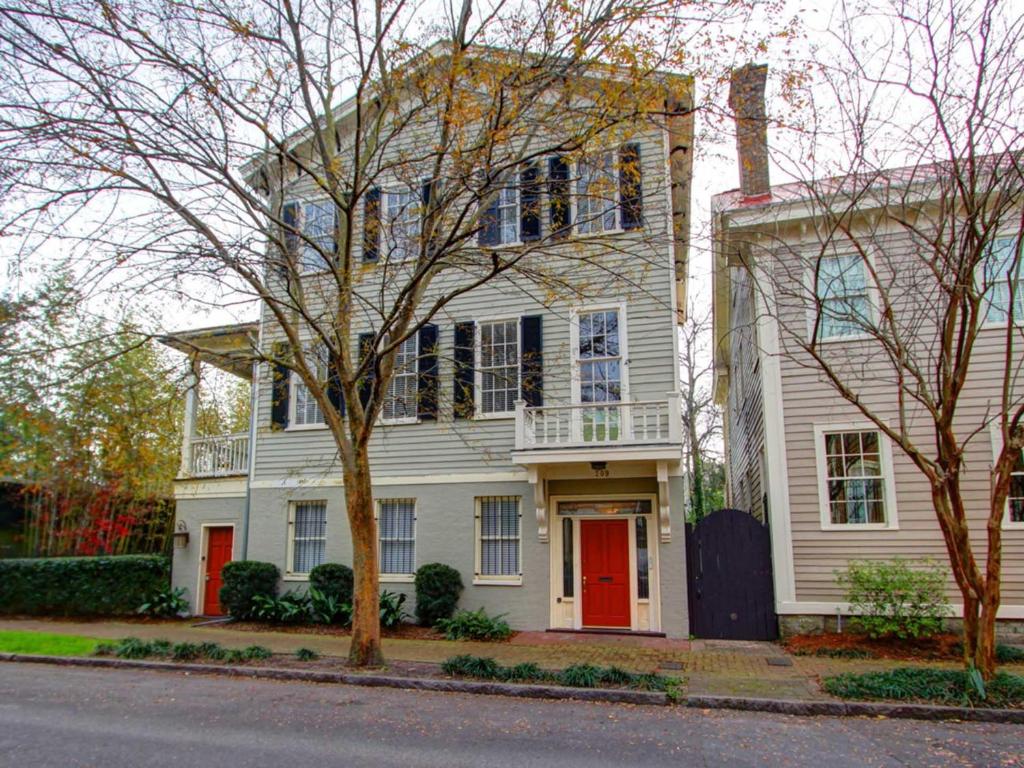 een wit huis met een rode deur op een straat bij Forsyth Park West Mansion in Savannah