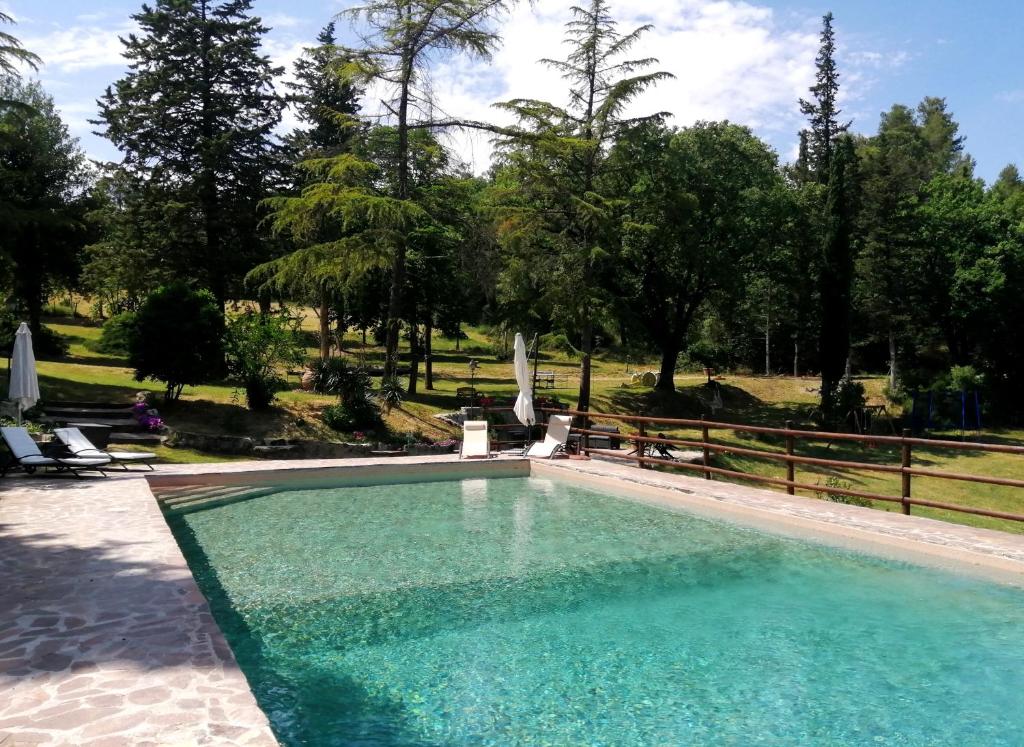 een zwembad in een tuin met een hek en bomen bij Podere Le Rote in Montecastelli