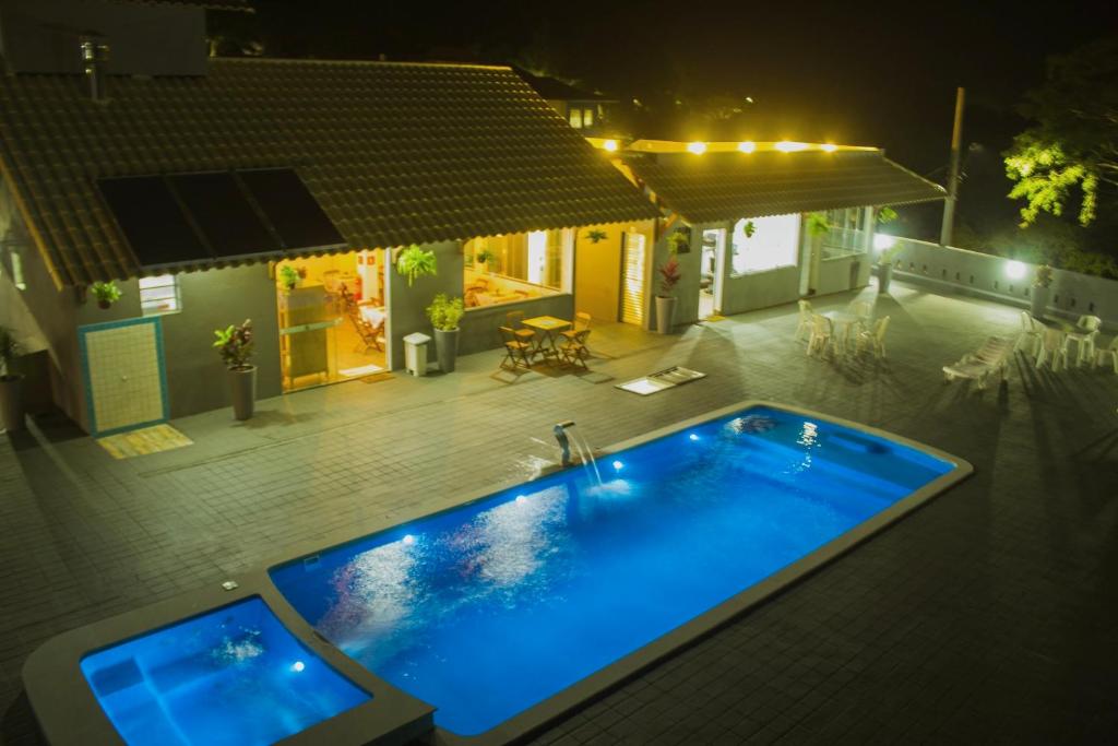 a swimming pool in the middle of a yard at night at CHALÉS GUARAÍPE in Guarapari