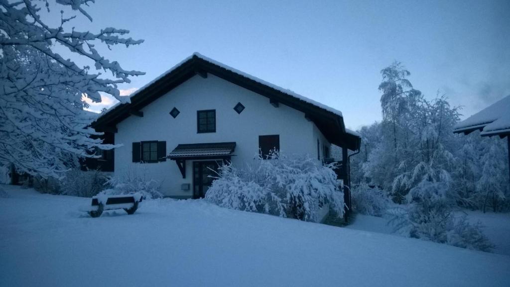 una casa cubierta de nieve con un banco delante en Feriendorf Reichenbach - Bgm.-Martin-Str. 10/2, en Nesselwang