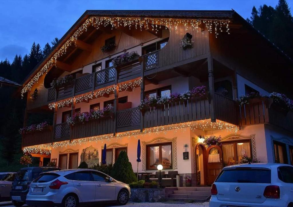 un edificio con coches estacionados frente a él en Garní Ladinia en Pescul