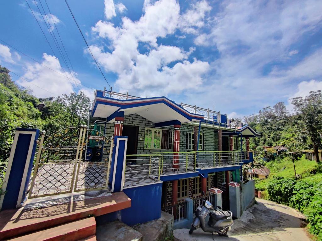una casa colorida con una valla delante en Jawa Homestay en Madikeri