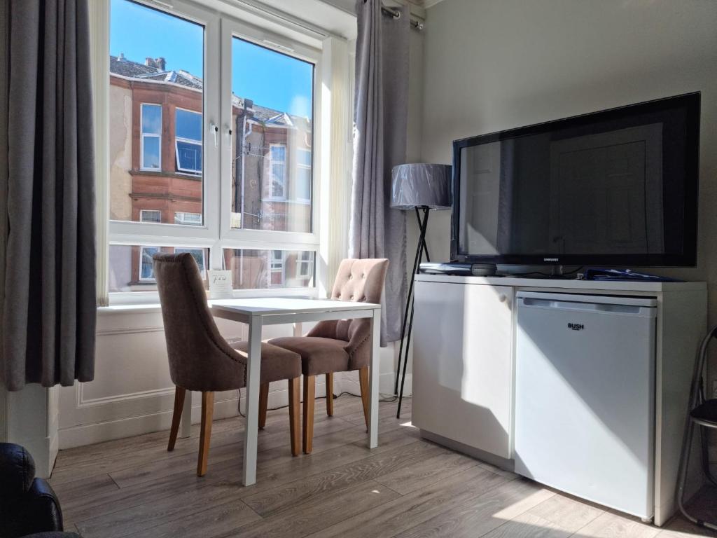 een woonkamer met een tafel, een tv en een raam bij Largs Apartment, Spacious & Modern 1 Bed near beach & shops in Largs