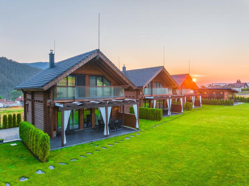 een rij houten huizen op een grasveld bij Samovilla in Govedartsi