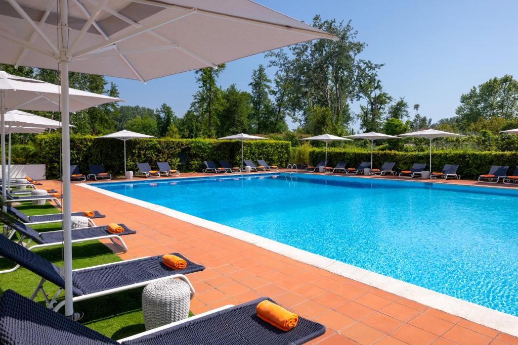 a swimming pool with chairs and umbrellas at UNAHOTELS Forte Dei Marmi in Forte dei Marmi