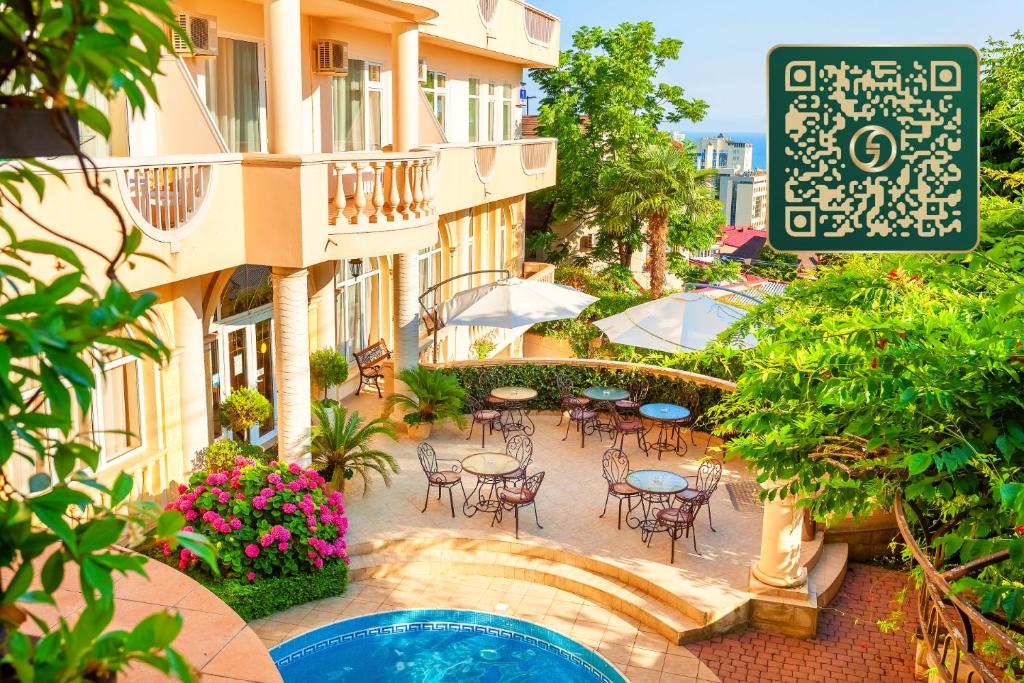 a courtyard with tables and chairs and a building at Hotel Grace Nairi in Sochi