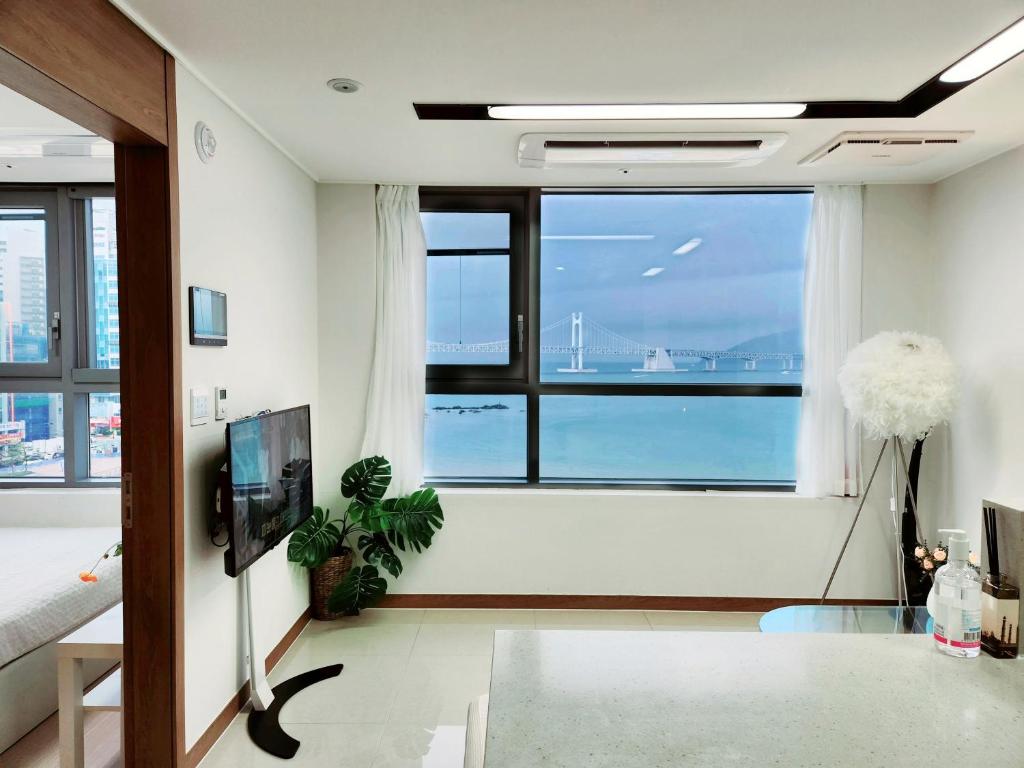 Hot place في بوسان: غرفة معيشة مع نافذة كبيرة مطلة على المحيط