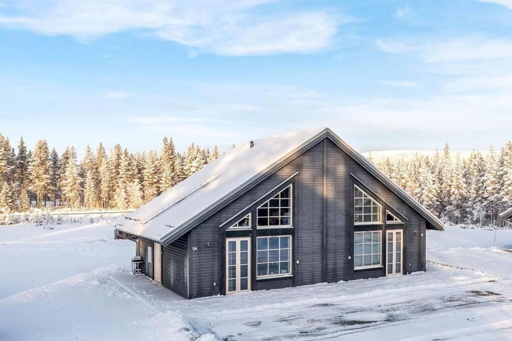 una casa negra en la nieve con árboles en Mysig fjällstuga i Idre Fjällfoten en Idre