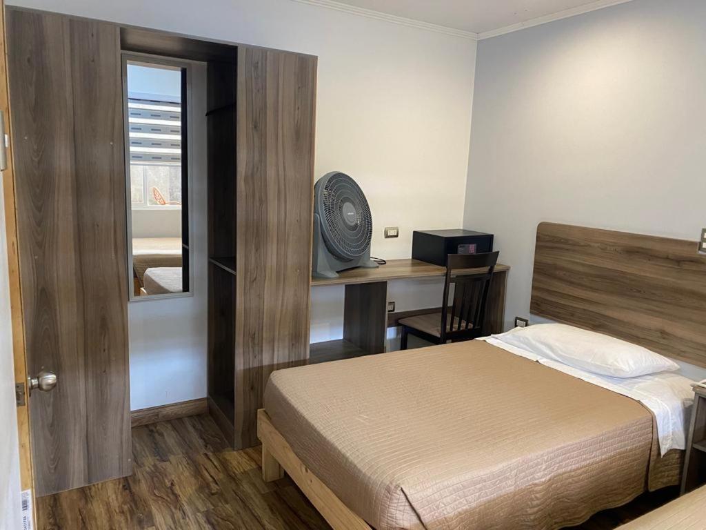 a bedroom with a bed and a desk with a window at Hotel Amaru Express in Arica