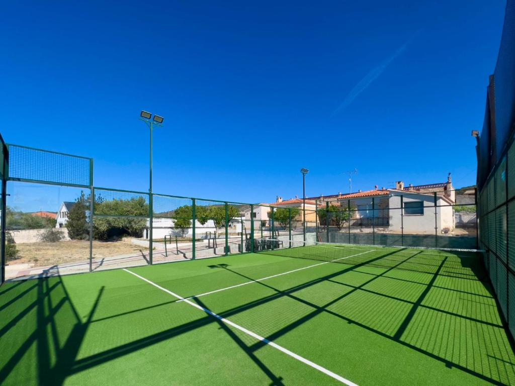 una pista de tenis con red en una pista de tenis en Villa con PISTA DE PADEL privada, piscina y Barbacoa, con más de 1800m2 de terreno, Villa Can Ramón en Papiolet