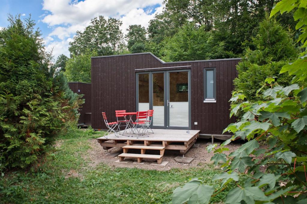 a small black cabin with a picnic table and chairs at Tiny House Nature 12 - Green Tiny Village Harz in Osterode