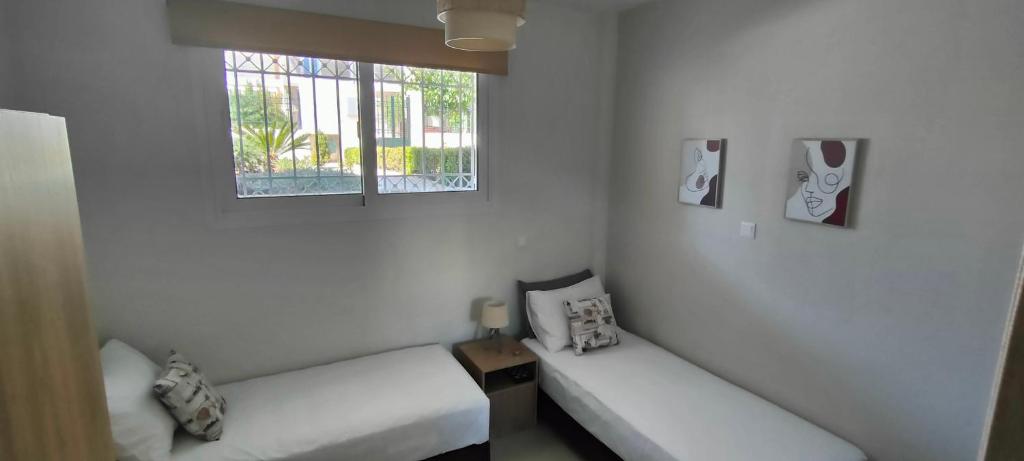 um quarto branco com 2 camas e uma janela em Natageo em Loutraki