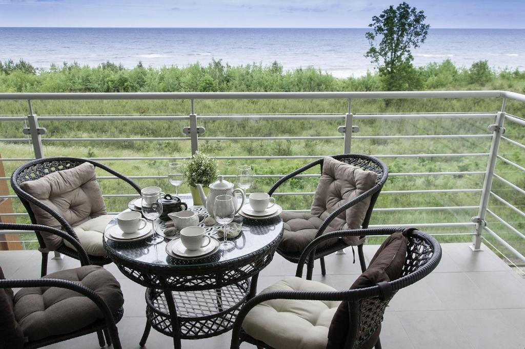 una mesa y sillas en un balcón con vistas al océano en Baltic View Apartment, en Dziwnówek