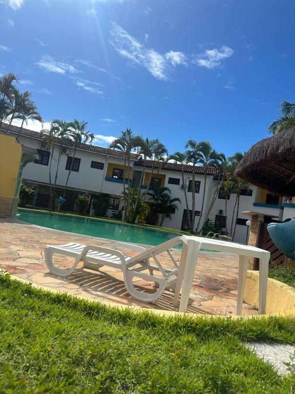 un banc blanc installé à côté d'une piscine dans l'établissement La Corte Residencial AC, à Porto Seguro