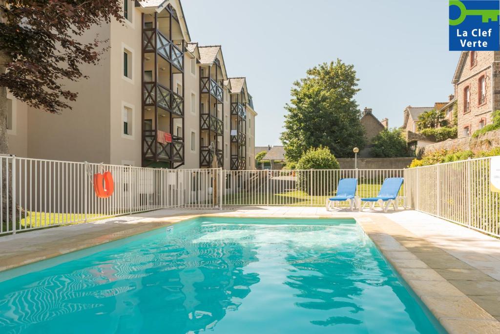 uma piscina com duas cadeiras azuis ao lado de um edifício em Résidence Pierre & Vacances Ty Mat em Saint Malo