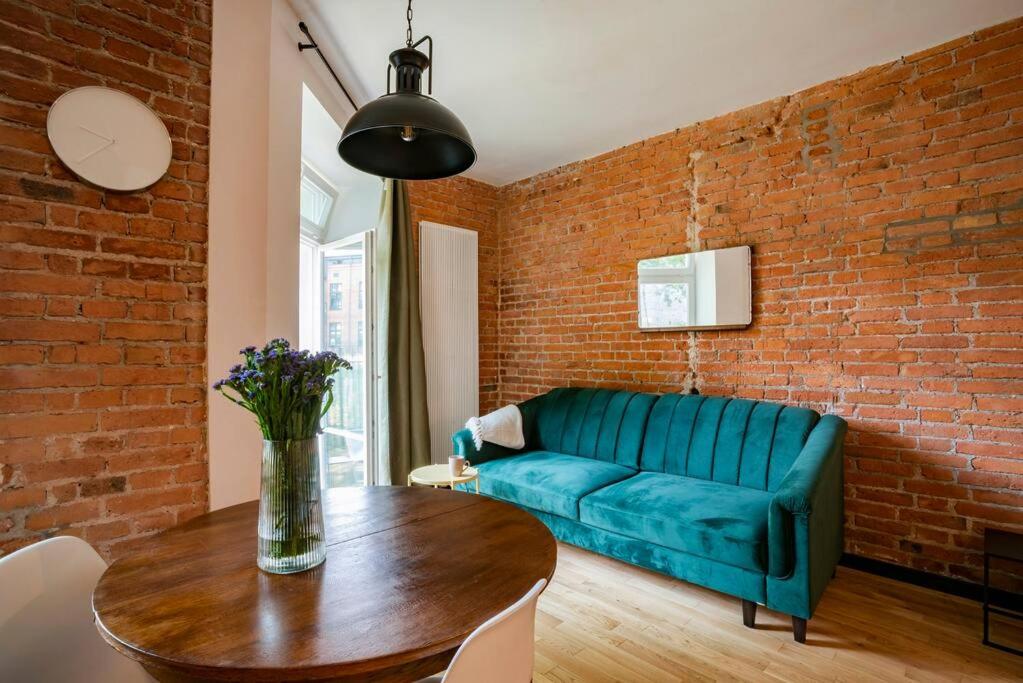 a living room with a blue couch and a brick wall at Cozy Studio 5 minut by Warsaw East in Warsaw