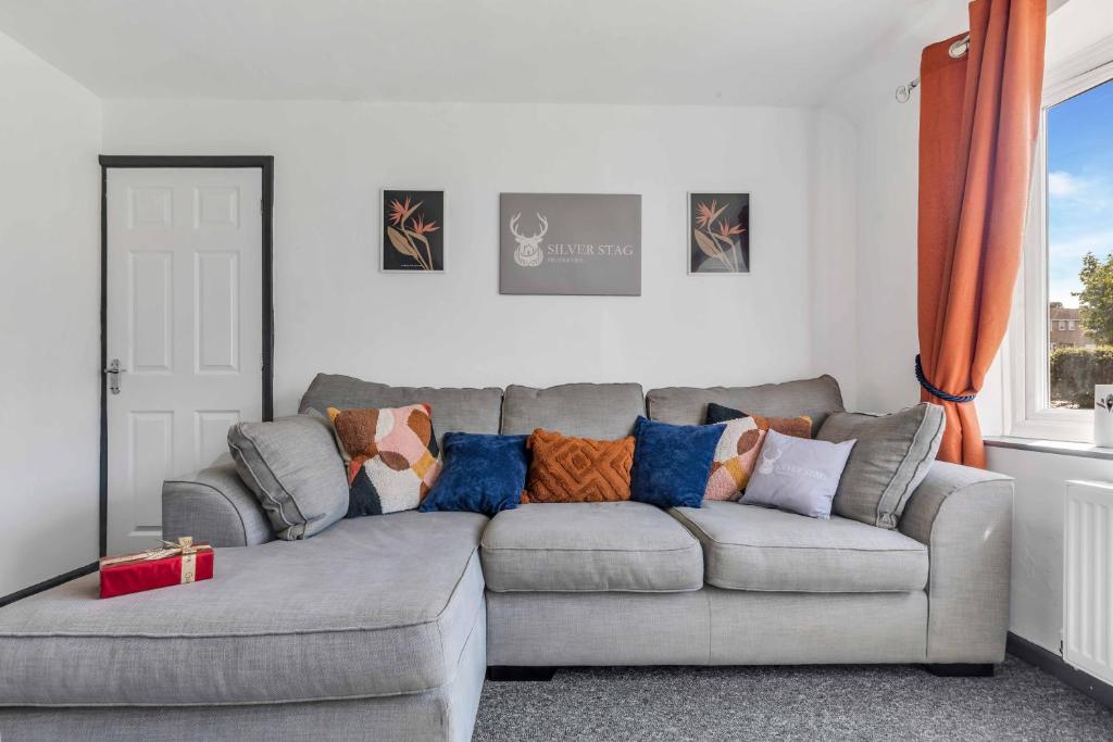 a living room with a gray couch with pillows at Silver Stag Properties, 4 BR in Ashby de la Zouch in Smisby